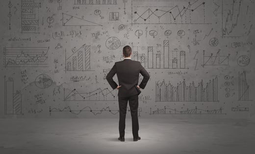 A successful confident businessman thinking about decisions, standing in front of wall full with graph pie charts and calculations concept