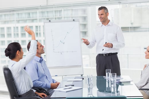 Businesswoman asking question during her colleagues presentation in bright office